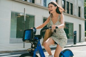 Femme souriante en faisant du vélo électrique en ville